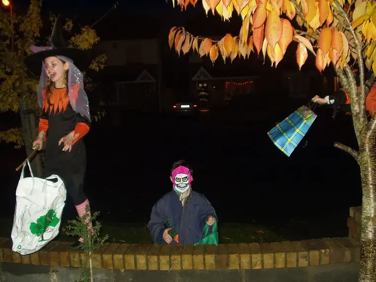 Children in Halloween costumes trick-or-treating at night